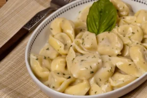 Close-up of Chicken Tortellini Alfredo garnished with parsley Chicken Tortellini Alfredo served with side salad and garlic bread