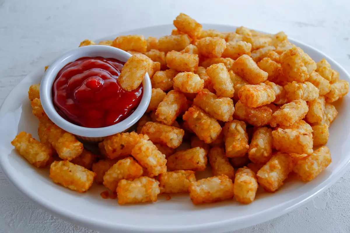 Frozen tater tots arranged in air fryer basket before cooking.